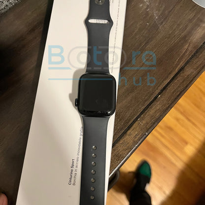 Smartwatch with a black band on a white box labeled 'Botta hub' on a wooden surface.